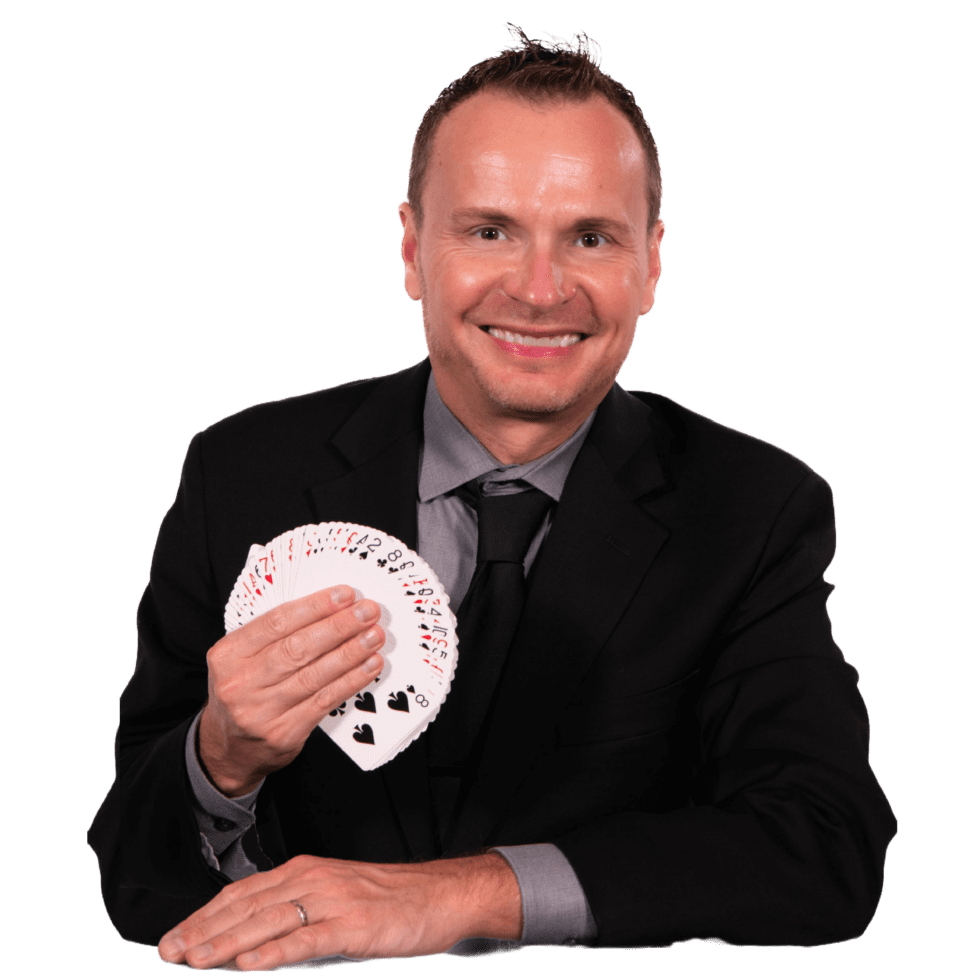 David Farr in a black suit, smiling and fanning a deck of playing cards